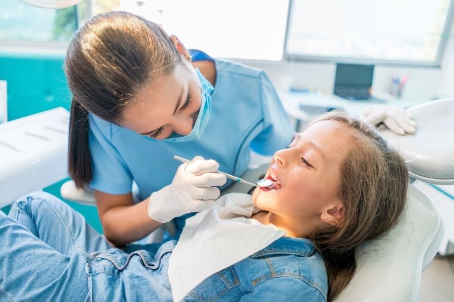 Pediatric dentist gently examining a young patient